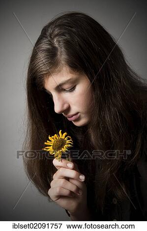 Stock Photo - "Pensive girl, aged 13, looking at a wilted sunflower, portrait". Fotosearch