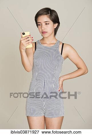 Pensive young woman reading text message on her mobile phone View Large Photo Image Stock Photo - Pensive young woman reading text message on her mobile phone. Fotosearch