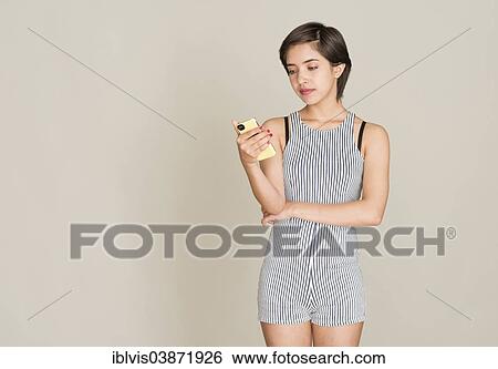 Stock Photograph - Pensive young woman reading text message on her mobile phone. Fotosearch