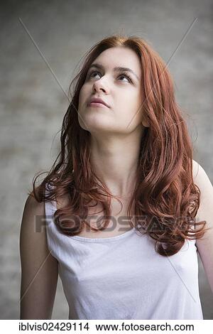 Pensive young woman with red hair looking up View Large Photo Image Picture - Pensive young woman with red hair looking up. Fotosearch