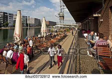 "People enjoying outdoor dining in the inner harbour, Duisburg, Ruhr district, North Rhine-Westphalia, Germany, Europe" View Large Photo Image Stock Image - "People enjoying outdoor dining in the inner harbour, Duisburg, Ruhr district, North Rhine-Westphalia, Germany, Europe". Fotosearch