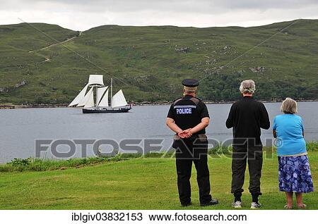 Stock Image - "People on the shore looking at the Dutch two-masted Topschoner Wylde Swan on Loch Broom, Ullapool, Caithness, Sutherland and Ross, Scottish Highlands, Scotland, United Kingdom, Europe". Fotosearch