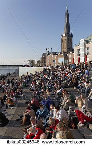"People sitting on a flight of steps in the evening sun, Burgplatz square with St Lambertus church, historic center, Dusseldorf, Rhineland, North Rhine-Westphalia, Germany, Europe" View Large Photo Image Stock Photograph - "People sitting on a flight of steps in the evening sun, Burgplatz square with St Lambertus church, historic center, Dusseldorf, Rhineland, North Rhine-Westphalia, Germany, Europe". Fotosearch