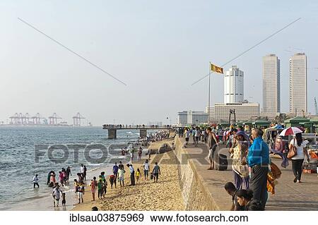 Stock Photo - "People walk along the beach promenade, Galle Face, skyscrapers and harbor behind, Colombo, Sri Lanka, Asia". Fotosearch