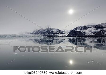 "Perfect reflection of mountains and glacial scenery in the pale sunshine of an overcast stormy day, Vikingebugt, Scoresbysund, Sermersooq, Greenland, North America" View Large Photo Image Stock Photo - "Perfect reflection of mountains and glacial scenery in the pale sunshine of an overcast stormy day, Vikingebugt, Scoresbysund, Sermersooq, Greenland, North America". Fotosearch