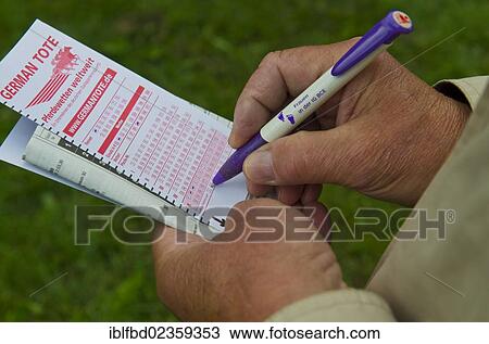 Stock Image - "Person placing a bet just before a horse race, Dresden, Saxony, Germany, Europe". Fotosearch