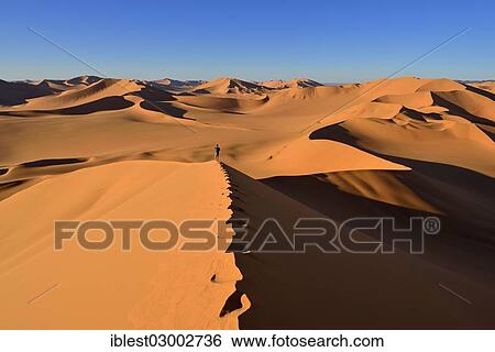 Stock Photograph - "Person walking on a sand dune, Sahara Desert, Immidir or Mouydir, Erg Mehejibad, Tamanrasset Province, Algeria, Africa". Fotosearch