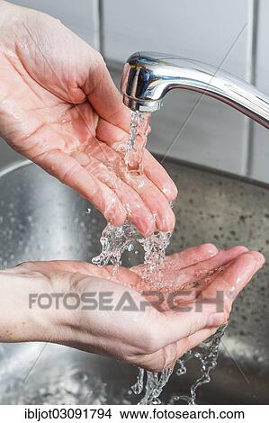 Picture - "Person washing their hands under running water from a faucet, symbolic image for water consumption". Fotosearch
