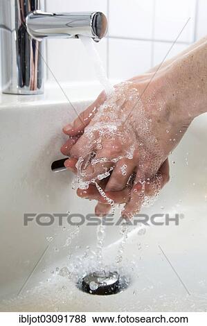 Stock Photo - "Person washing their hands under running water from a faucet, symbolic image for water consumption". Fotosearch