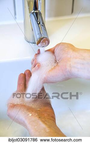 Stock Photograph - "Person washing their hands under running water from a faucet, symbolic image for water consumption". Fotosearch
