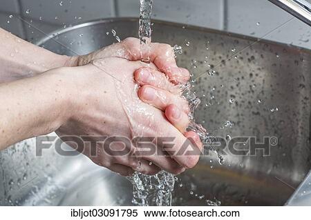 Stock Photography - "Person washing their hands under running water from a faucet, symbolic image for water consumption". Fotosearch