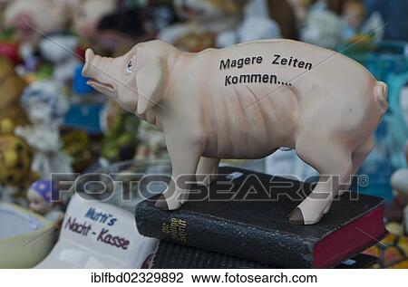 Stock Image - "Piggy bank labelled """"Magere Zeiten kommen"""", German for """"lean times will come"""", standing on a bible, at the weekly flea market, Dresden, Saxony, Germany, Europe". Fotosearch