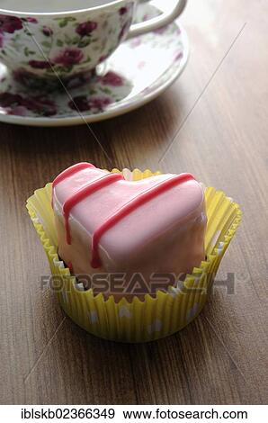 Pink heart-shaped petit four on a wooden surface beside a coffee cup View Large Photo Image Stock Photo - Pink heart-shaped petit four on a wooden surface beside a coffee cup. Fotosearch