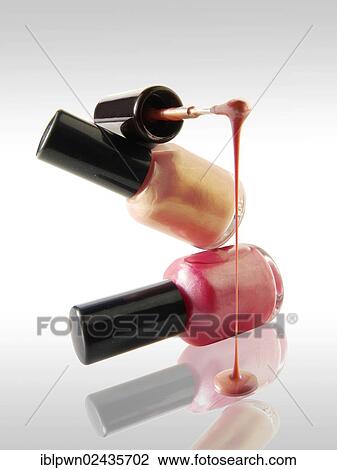 Stock Image - Pink nail varnish dripping from a nail varnish brush balanced on a nail varnish bottle. Fotosearch