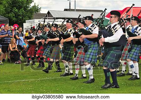 Stock Image - "Pipe band marching in unison on the sports ground at the Highland Games, Dufftown, Moray, Highlands, Scotland, United Kingdom, Europe". Fotosearch