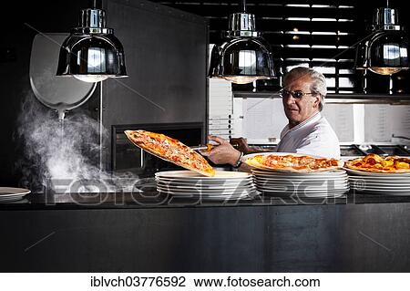 Pizza baker taking the finished pizza out of the oven with a pizza shovel View Large Photo Image Stock Image - Pizza baker taking the finished pizza out of the oven with a pizza shovel. Fotosearch