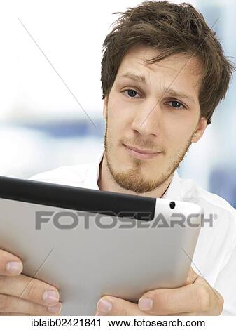 Portrait of a businessman holding an iPad, serious, stressed, anxious, having problems, crisis, in the office View Large Photo Image Stock Image - Portrait of a businessman holding an iPad, serious, stressed, anxious, having problems, crisis, in the office. Fotosearch