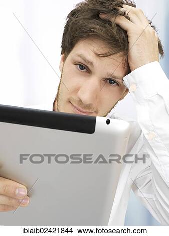 Picture - Portrait of a businessman, iPad, thoughtful, focused, reflective, hand on head. Fotosearch