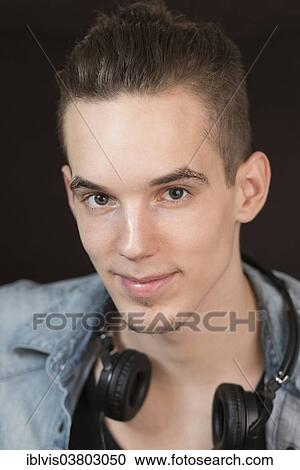 Stock Image - Portrait of a confident and carefree young adult male with earphones. Fotosearch
