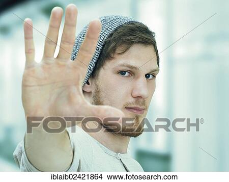 Portrait of a young man with a bear with a woolly hat, defensive gesture, irritated View Large Photo Image Picture - Portrait of a young man with a bear with a woolly hat, defensive gesture, irritated. Fotosearch