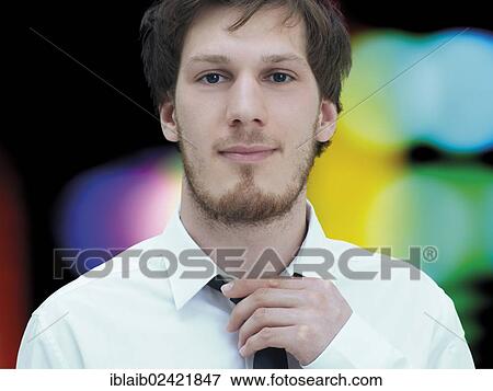 Portrait of a young man with a beard, white shirt, straightening tie View Large Photo Image Stock Photo - Portrait of a young man with a beard, white shirt, straightening tie. Fotosearch