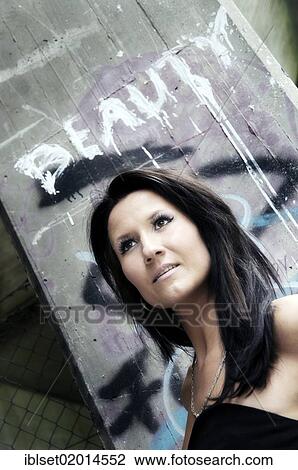 "Portrait of a young woman standing in front of a wall with graffiti on it, lettering """"Beauty""""" View Large Photo Image Stock Image - "Portrait of a young woman standing in front of a wall with graffiti on it, lettering """"Beauty""""". Fotosearch