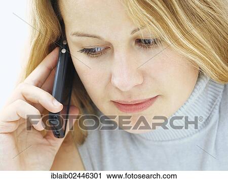 Stock Image - "Portrait of a young woman with a serious face, concentrated, mobile phone". Fotosearch
