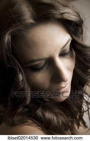 Stock Image - "Portrait of a young woman with long eyelashes, looking down". Fotosearch