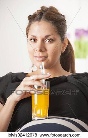 Stock Photo - Pregnant woman drinking a glass of orange soda. Fotosearch