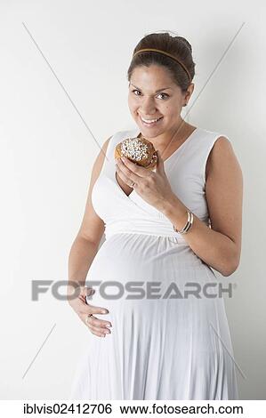 Pregnant woman eating a cinnamon roll View Large Photo Image Stock Photograph - Pregnant woman eating a cinnamon roll. Fotosearch