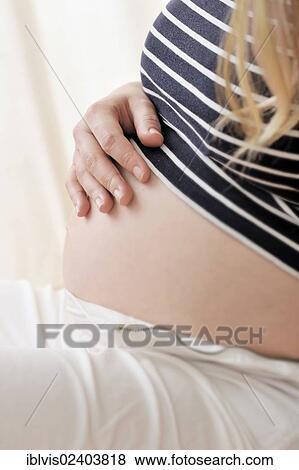 Pregnant woman holding a hand on her belly View Large Photo Image Stock Photo - Pregnant woman holding a hand on her belly. Fotosearch