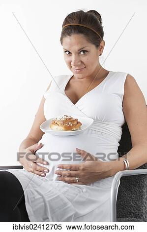 Pregnant woman holding hands on her stomach and resting a plate with a sweet bun on her belly View Large Photo Image Stock Photography - Pregnant woman holding hands on her stomach and resting a plate with a sweet bun on her belly. Fotosearch