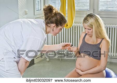Stock Photo - "Pregnant woman recieving homeopathic medicine from her midwife during delivery, Germany, Europe". Fotosearch