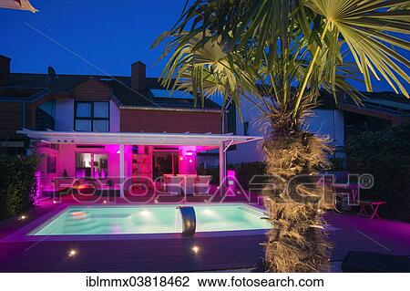 "Private terraced house with a conservatory, a pool, a terrace and a palm tree with display lighting at night, Germany, Europe" View Large Photo Image Stock Image - "Private terraced house with a conservatory, a pool, a terrace and a palm tree with display lighting at night, Germany, Europe". Fotosearch