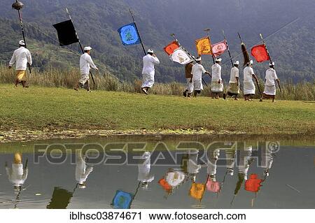 Stock Image - "Procession, flags, reflections in the water, Lake Bratan, Bali, Indonesia, Asia". Fotosearch