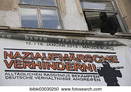 "Protest against a neo-Nazi march, a masked man is standing at the window of a left-wing housing project, libertarian centre, on the route of the neo-Nazi march, Magdeburg, Magdeburg, Saxony-Anhalt, Germany, Europe" View Large Photo Image Stock Image - "Protest against a neo-Nazi march, a masked man is standing at the window of a left-wing housing project, libertarian centre, on the route of the neo-Nazi march, Magdeburg, Magdeburg, Saxony-Anhalt, Germany, Europe". Fotosearch