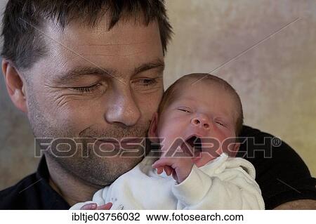 Stock Image - "Proud father holding his newborn baby boy in his arms, Germany, Europe". Fotosearch