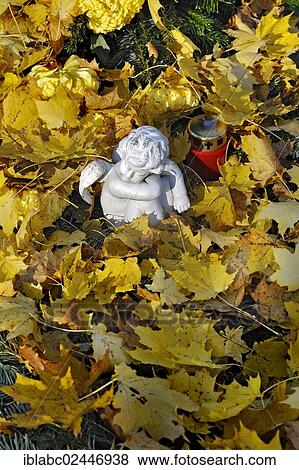 Stock Photo - "Putto and votive candle with autumn leaves on the Ostfriedhof or East Cemetery, Munich, Bavaria, Germany, Europe". Fotosearch