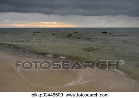 Stock Photo - "Rain front, dramatic cloudy sky at sunset, stones on the beach, Dranske, Mecklenburg-Western Pomerania, Germany, Europe". Fotosearch