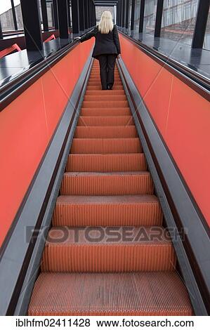 "Rear view of a blonde woman on a red escalator, Essen, North Rhine-Westphalia, Germany, Europe" View Large Photo Image Stock Photo - "Rear view of a blonde woman on a red escalator, Essen, North Rhine-Westphalia, Germany, Europe". Fotosearch