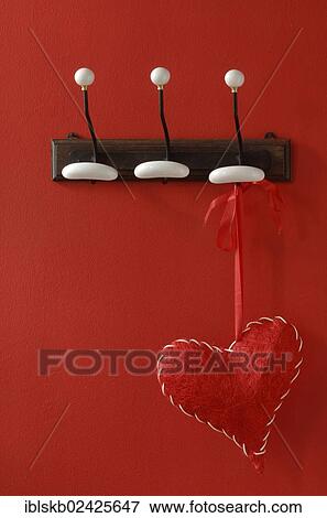 Red fabric heart hanging from nostalgic clothes hooks on a red wall View Large Photo Image Stock Photo - Red fabric heart hanging from nostalgic clothes hooks on a red wall. Fotosearch