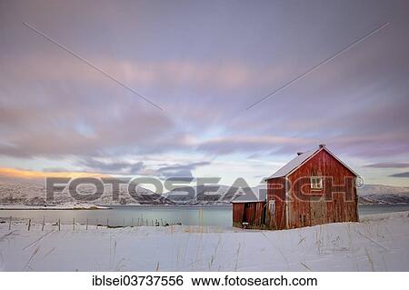 Stock Photograph - "Red fishing hut before fjord in winter landscape, Sommeroya, Tromso, â€ªTroms, Northern Norway, Norway, Europe". Fotosearch