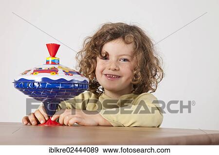 "Red-haired girl, 5 years old, holding a spinning top" View Large Photo Image Stock Photo - "Red-haired girl, 5 years old, holding a spinning top". Fotosearch