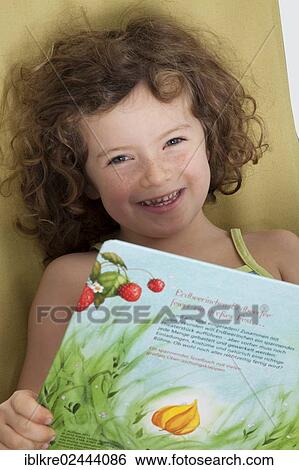 "Red-haired girl, 5 years old, sitting on a deck chair with a children's book" View Large Photo Image Stock Photograph - "Red-haired girl, 5 years old, sitting on a deck chair with a children's book". Fotosearch