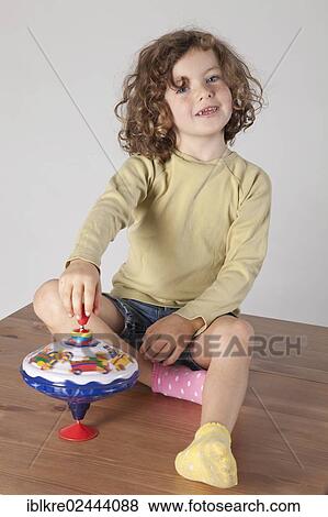 "Red-haired girl, 5 years old, using a spinning top" View Large Photo Image Stock Photo - "Red-haired girl, 5 years old, using a spinning top". Fotosearch