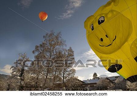 "Red hot air balloon travelling against a blue sky, yellow hot air balloon in the shape of a smiling face being inflated, 12th balloon festival of Tegernsee, Montgolfiade, Bad Wiessee, Tegernsee, Bavaria, Germany, Europe" View Large Photo Image Stock Photography - "Red hot air balloon travelling against a blue sky, yellow hot air balloon in the shape of a smiling face being inflated, 12th balloon festival of Tegernsee, Montgolfiade, Bad Wiessee, Tegernsee, Bavaria, Germany, Europe". Fotosearch