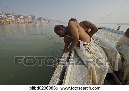 Stock Photography - "Remains of the cremation of a family member are offered to the holy river Ganges, Varanasi, India, Asia". Fotosearch
