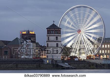 "Rheinfront promenade with Schlossturm tower and an illuminated ferris wheel, historic town centre, Dusseldorf, North Rhine-Westphalia, Germany, Europe" View Large Photo Image Stock Photo - "Rheinfront promenade with Schlossturm tower and an illuminated ferris wheel, historic town centre, Dusseldorf, North Rhine-Westphalia, Germany, Europe". Fotosearch
