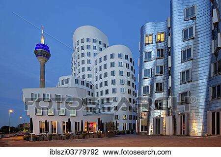 Stock Image - "Rheinturm or Rhine Tower with two of the Gehry buildings at Neuer Zollhof, Medienhafen harbour, Dusseldorf, North Rhine-Westphalia, Germany, Europe". Fotosearch