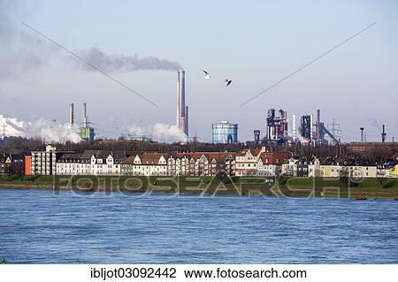 "Rhine at Duisburg-Laar with houses behind the dyke, industrial backdrop of the ThyssenKrupp steel mill in Duisburg-Bruckhausen at back, Duisburg, North Rhine-Westphalia, Germany, Europe" View Large Photo Image Stock Image - "Rhine at Duisburg-Laar with houses behind the dyke, industrial backdrop of the ThyssenKrupp steel mill in Duisburg-Bruckhausen at back, Duisburg, North Rhine-Westphalia, Germany, Europe". Fotosearch